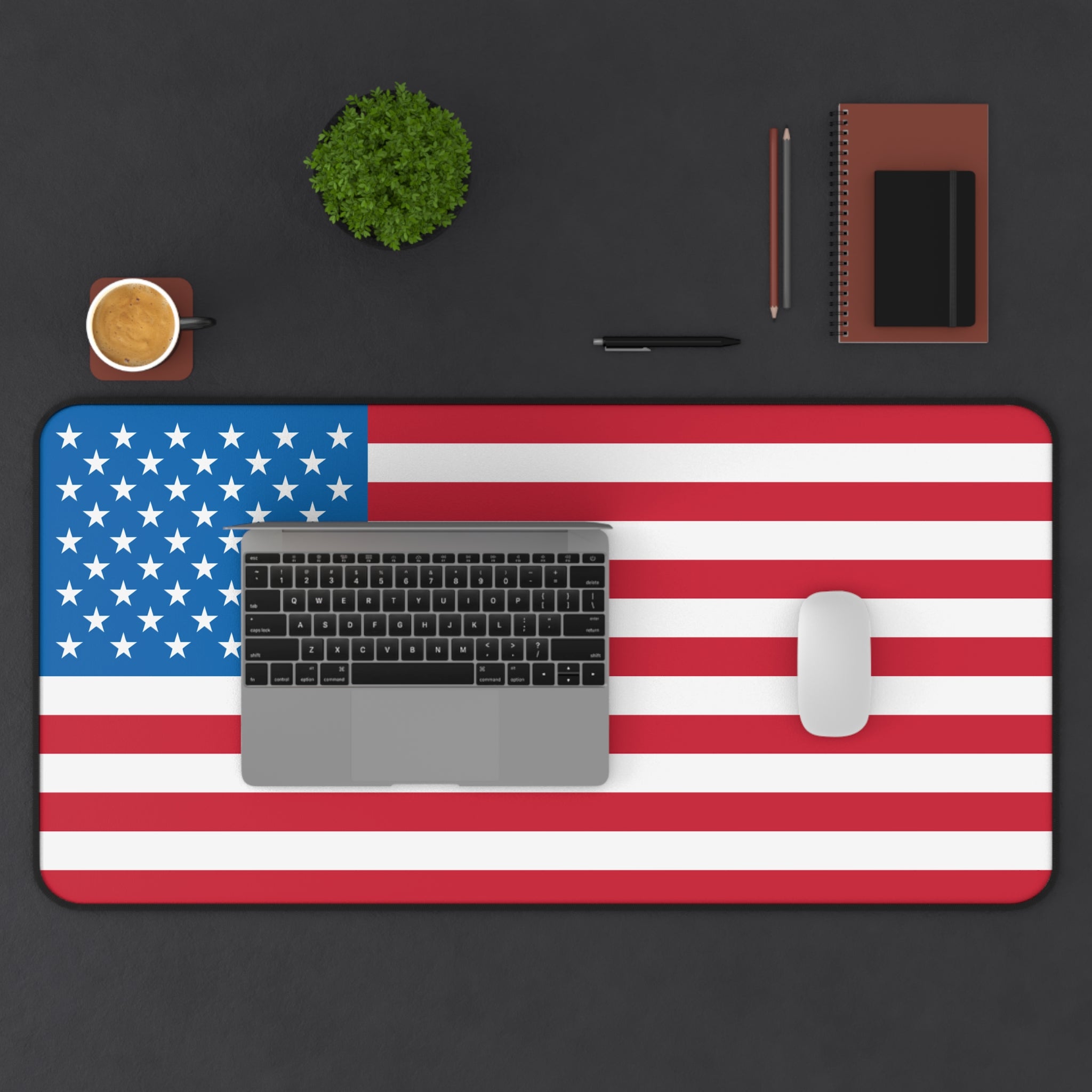 Desk setup with an American flag desk pad, laptop, mouse, and office supplies on a black background.