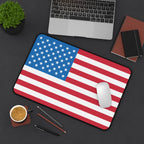 American flag mouse pad on a desk with a laptop, coffee, and office supplies.