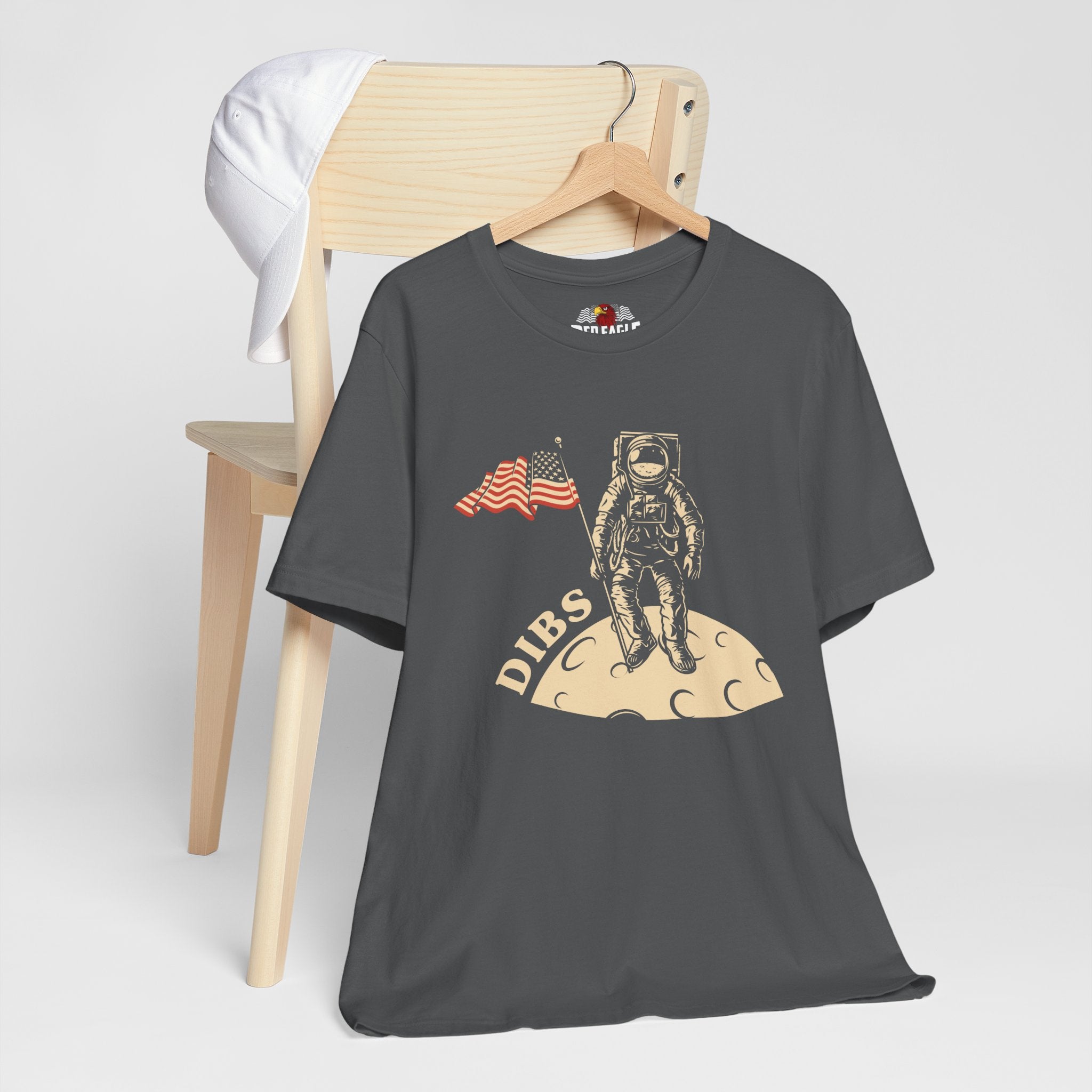 Asphalt t-shirt with astronaut graphic and 'DIBS' text on a wooden chair.