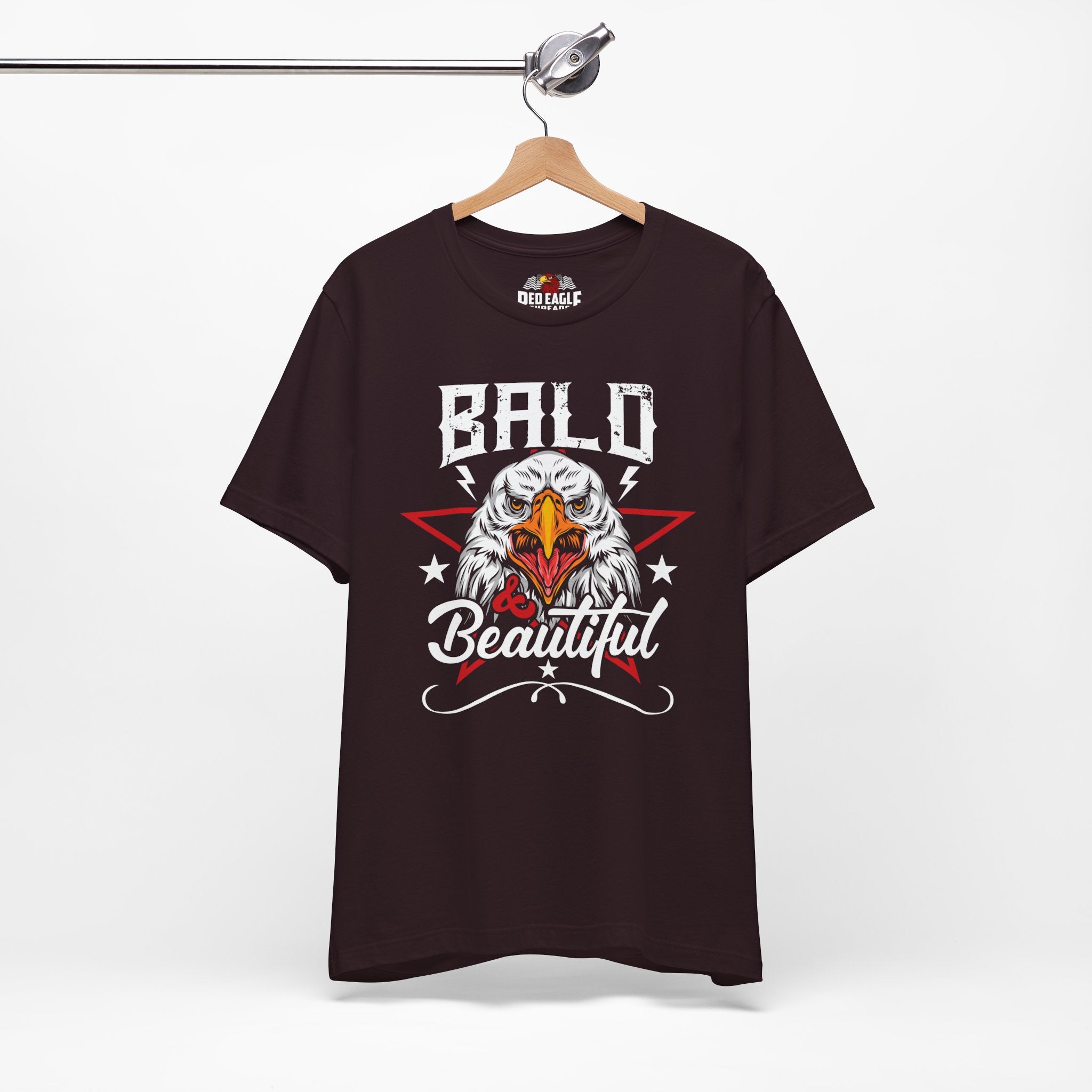 Oxblood Black t-shirt with bald eagle graphic and 'Bald is Beautiful' text on a hanger against a white background.