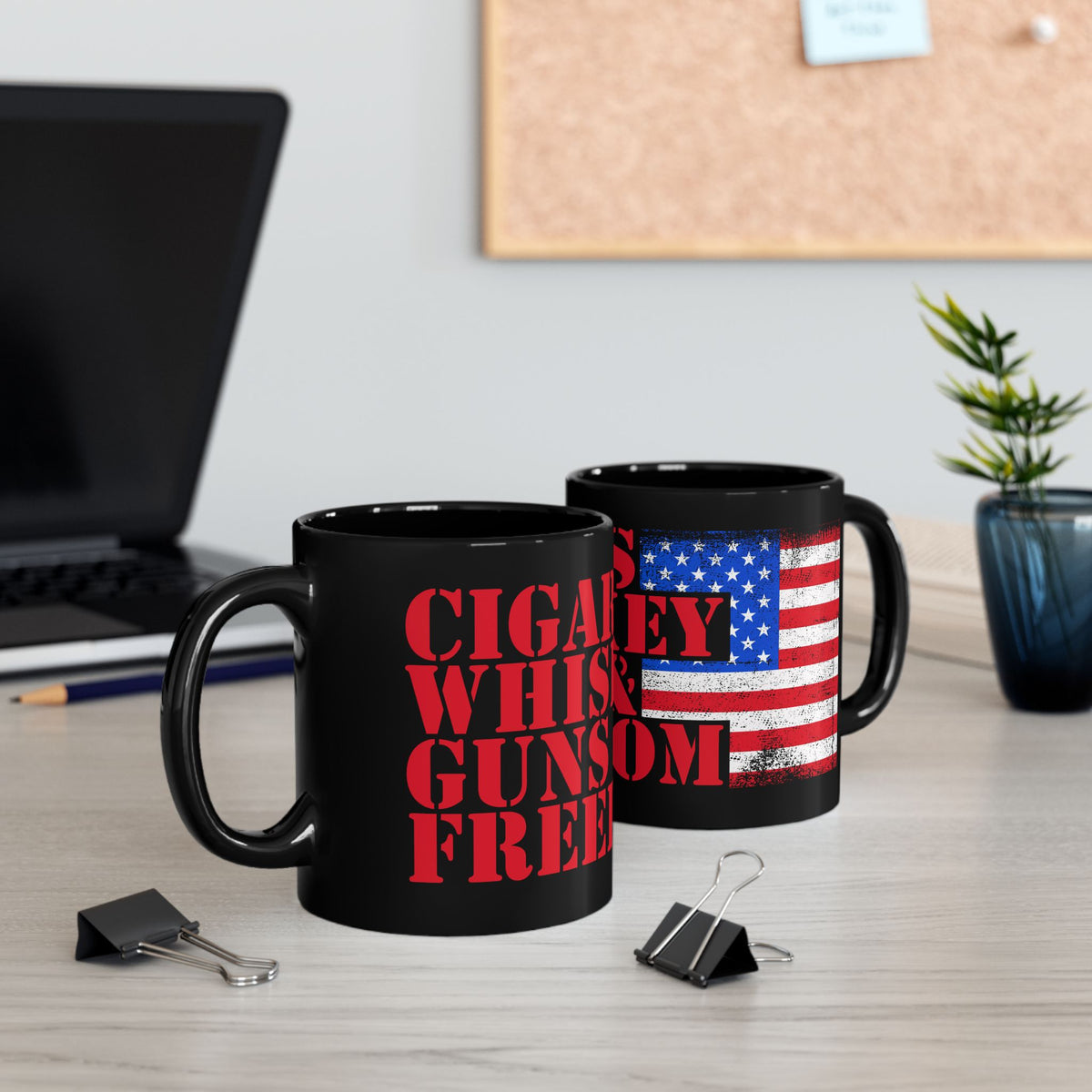 Two black mugs on a desk with one featuring red text and the other an American flag design.