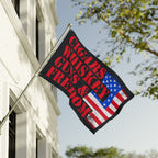 Flag with text 'Cigars, Whiskey, Guns & Freedom' on a building exterior.