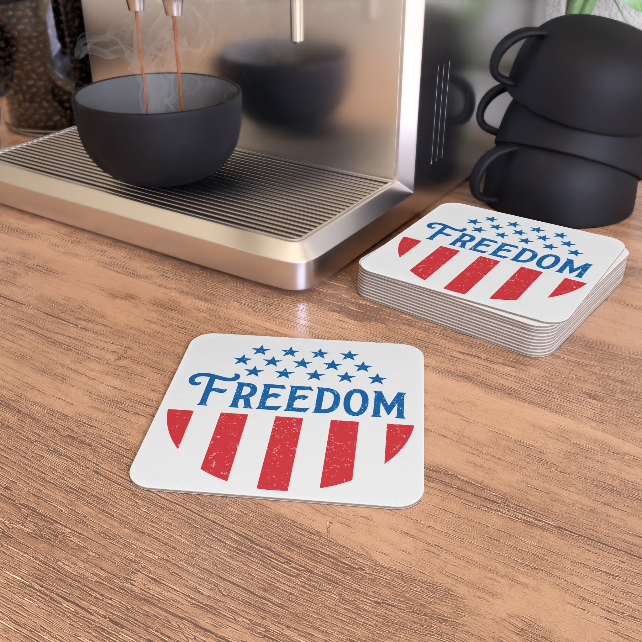 Coasters with 'Freedom' design on a wooden surface next to a coffee machine.