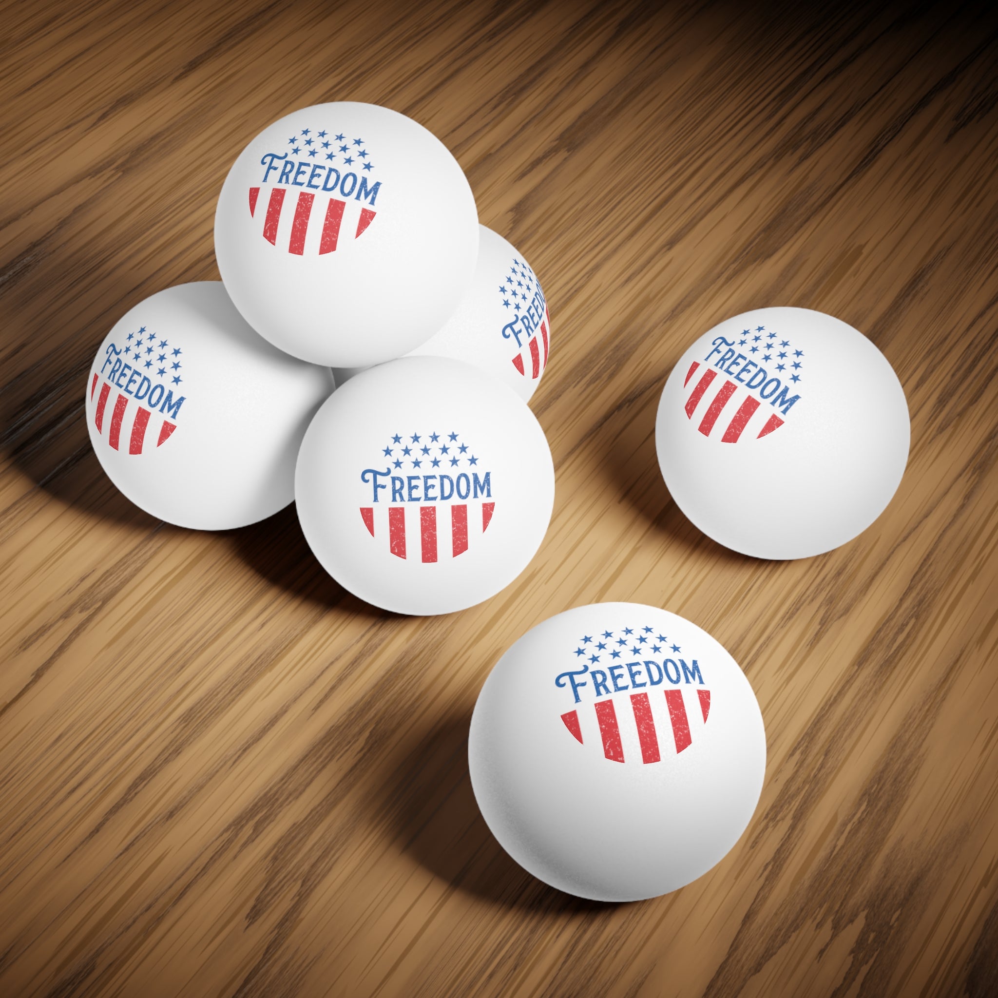 White ping pong balls with 'Freedom' and American flag design on a wooden surface