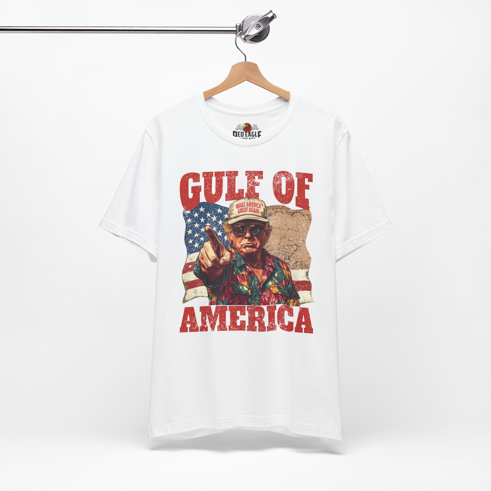 White t-shirt with graphic design of a person holding a gun and 'Gulf of America' text, hanging on a wooden hanger.