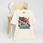 Natural t-shirt with graphic design of a person holding a phone in front of an American flag, sitting in a chair, with 'Gulf of America' text on a white background.