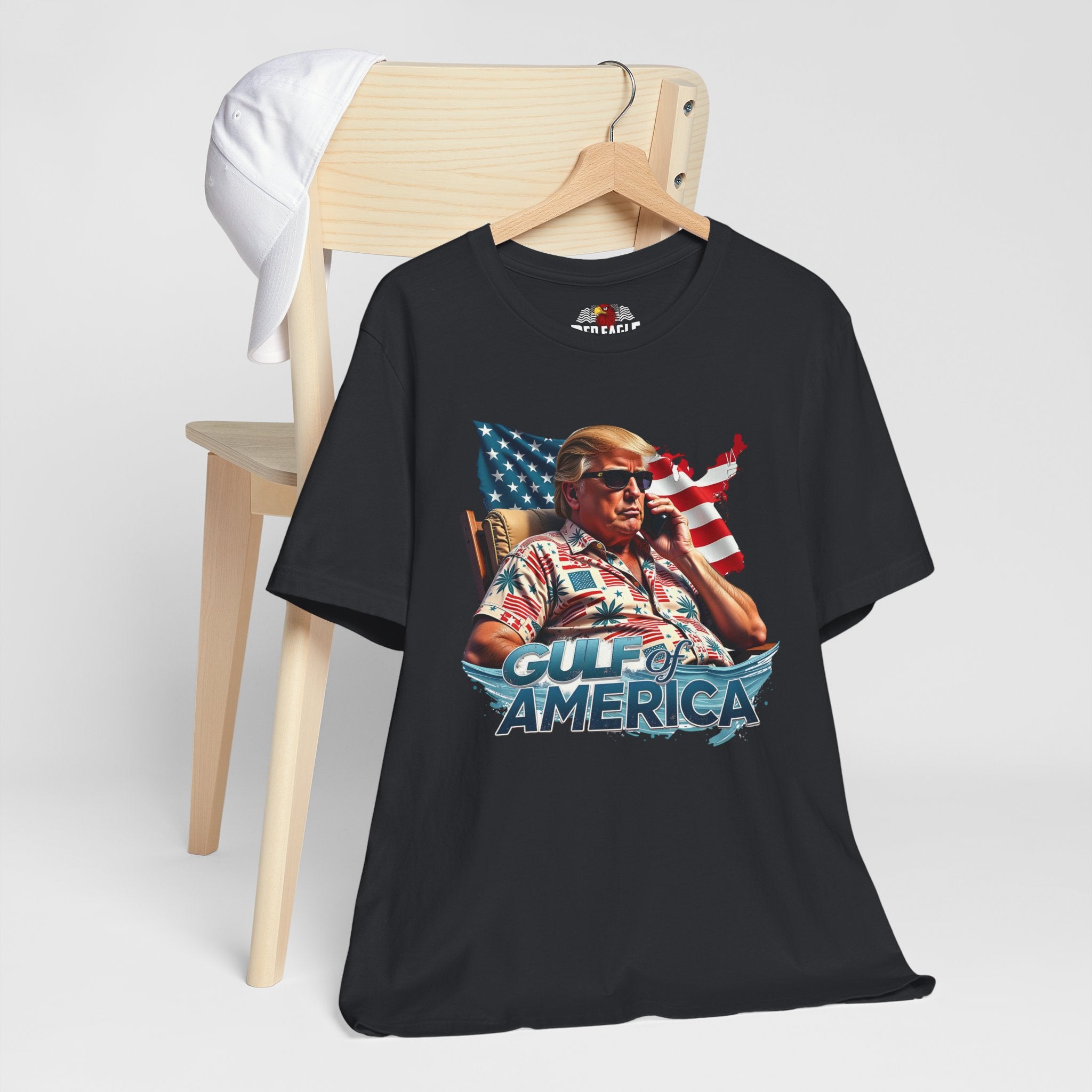 Vintage Black t-shirt with graphic design of a person holding a phone in front of an American flag, sitting in a chair, with 'Gulf of America' text on a white background.