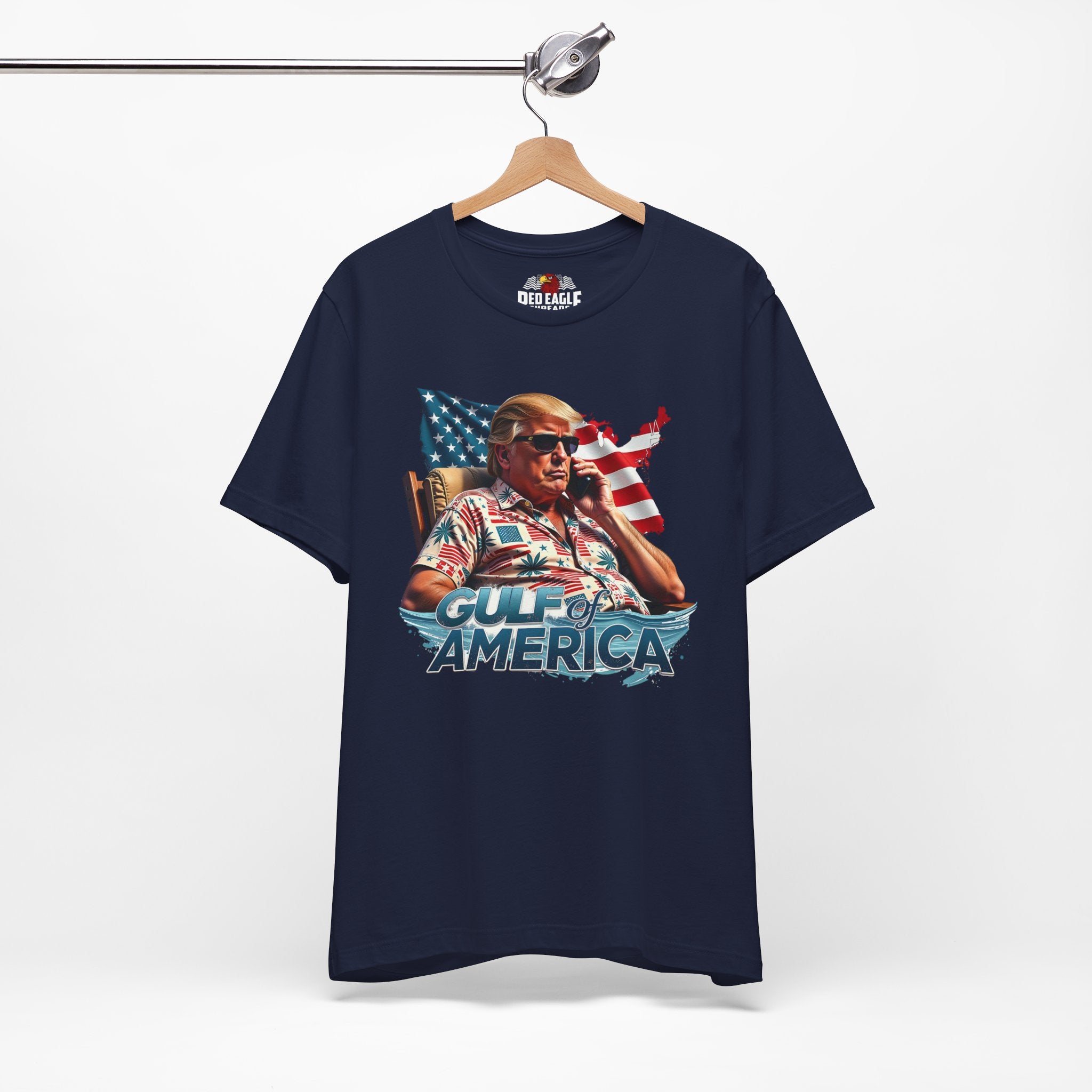 Navy blue t-shirt with graphic design of a person holding an American flag, hanging on a wooden hanger against a white background.
