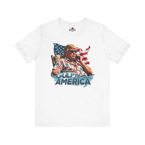 White t-shirt with graphic design of a person on a phone with an American flag, text 'Gulf of America', and a logo on a white background.