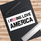 Black folder with 'I F***ING LOVE AMERICA' text and American flag on a wooden surface with pens and a ruler.
