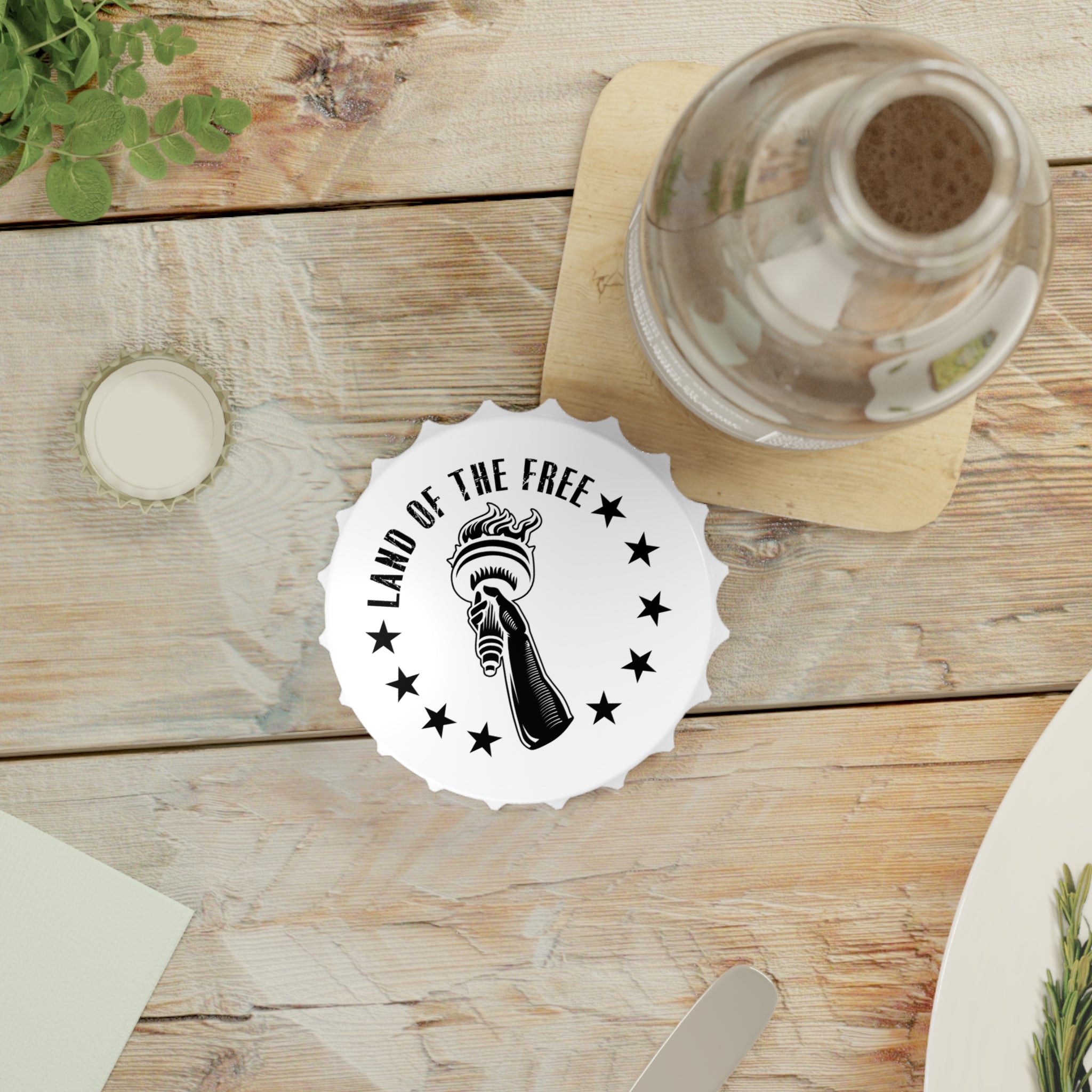 Table setting with white bottle opener fridge magnet with 'Land of the Free' logo on a wooden surface