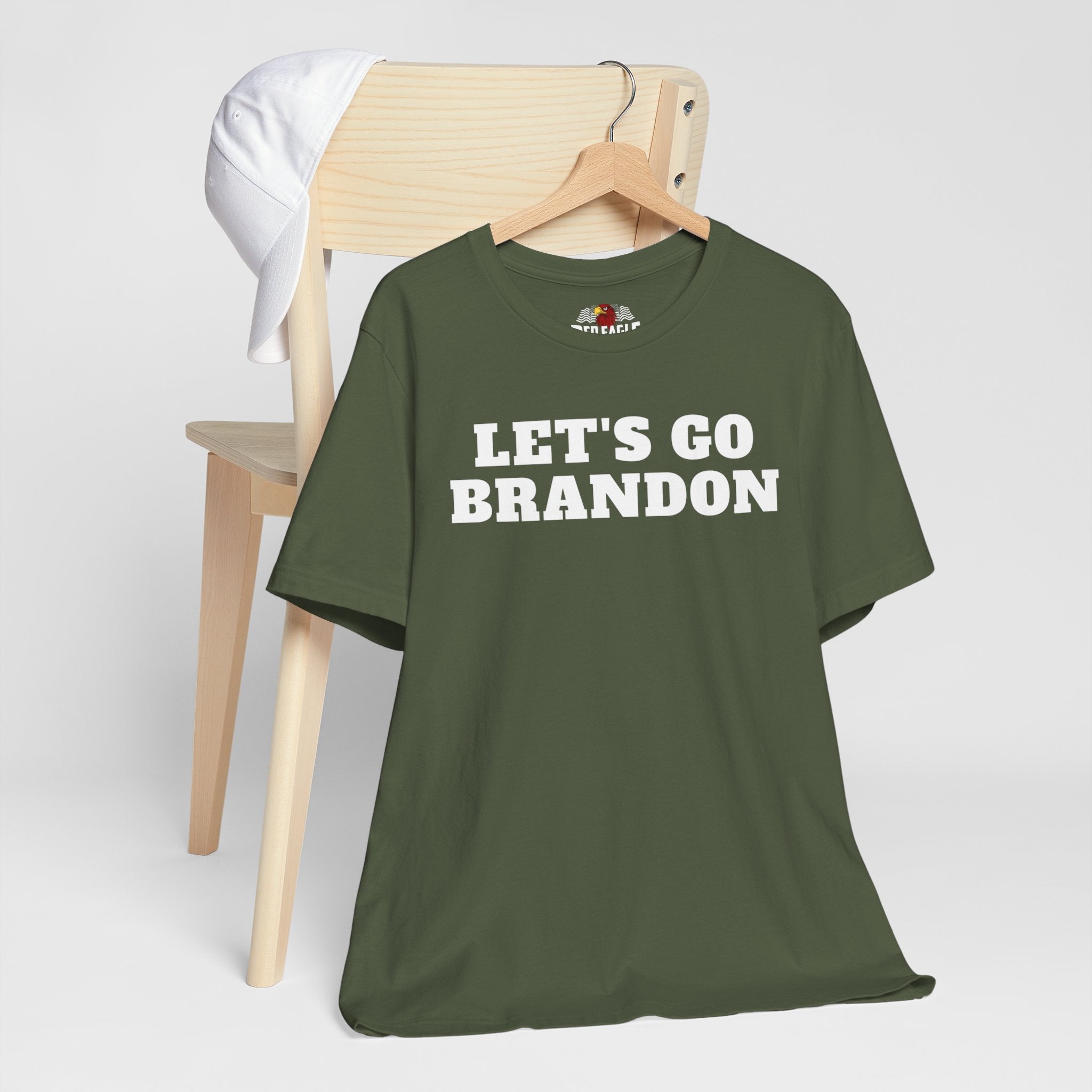 Military Green t-shirt with 'LET'S GO BRANDON' text on a wooden chair against a white background