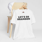 White t-shirt with 'LET'S GO BRANDON' text on a wooden chair against a white background