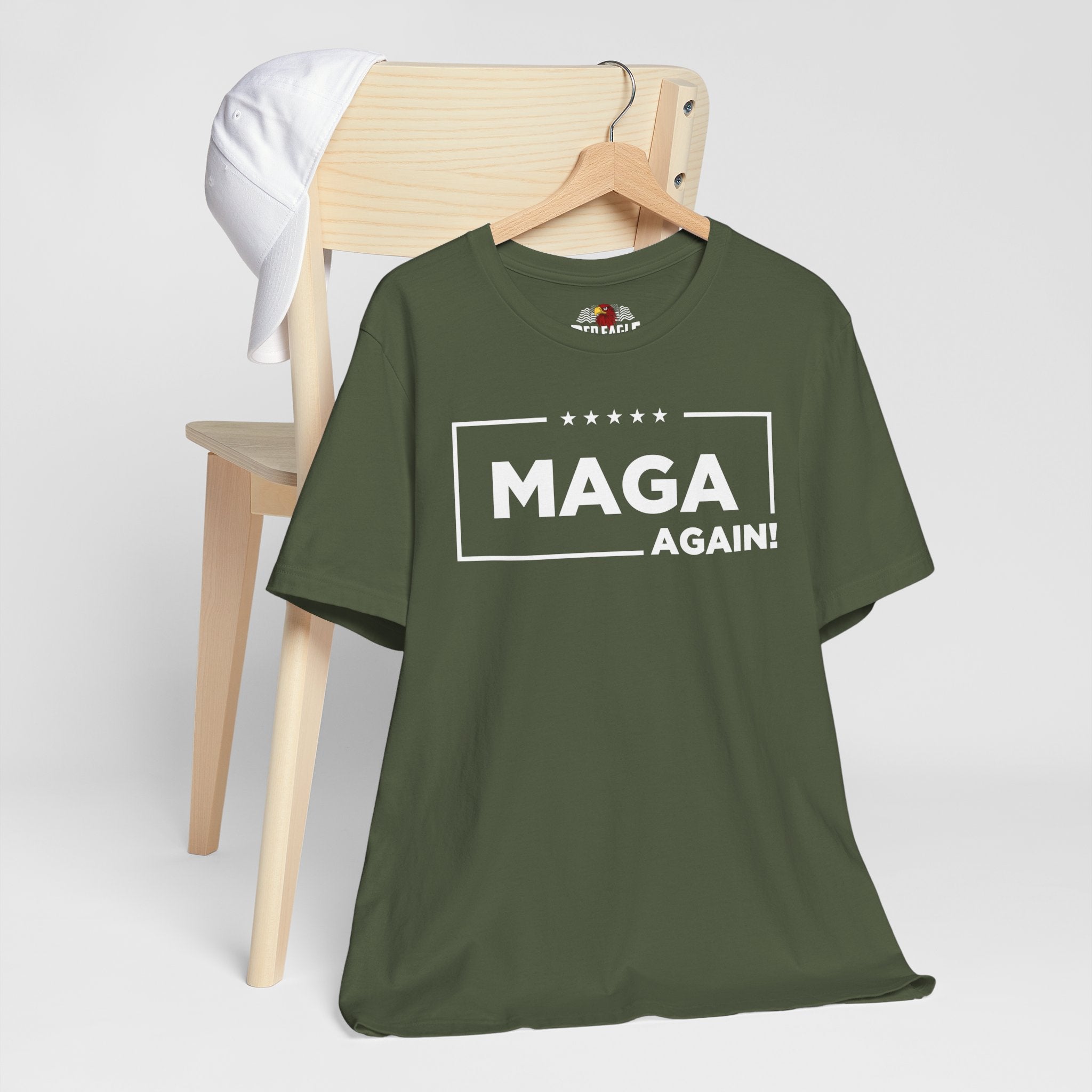 Green t-shirt with 'MAGA AGAIN!' text on a wooden chair against a white background