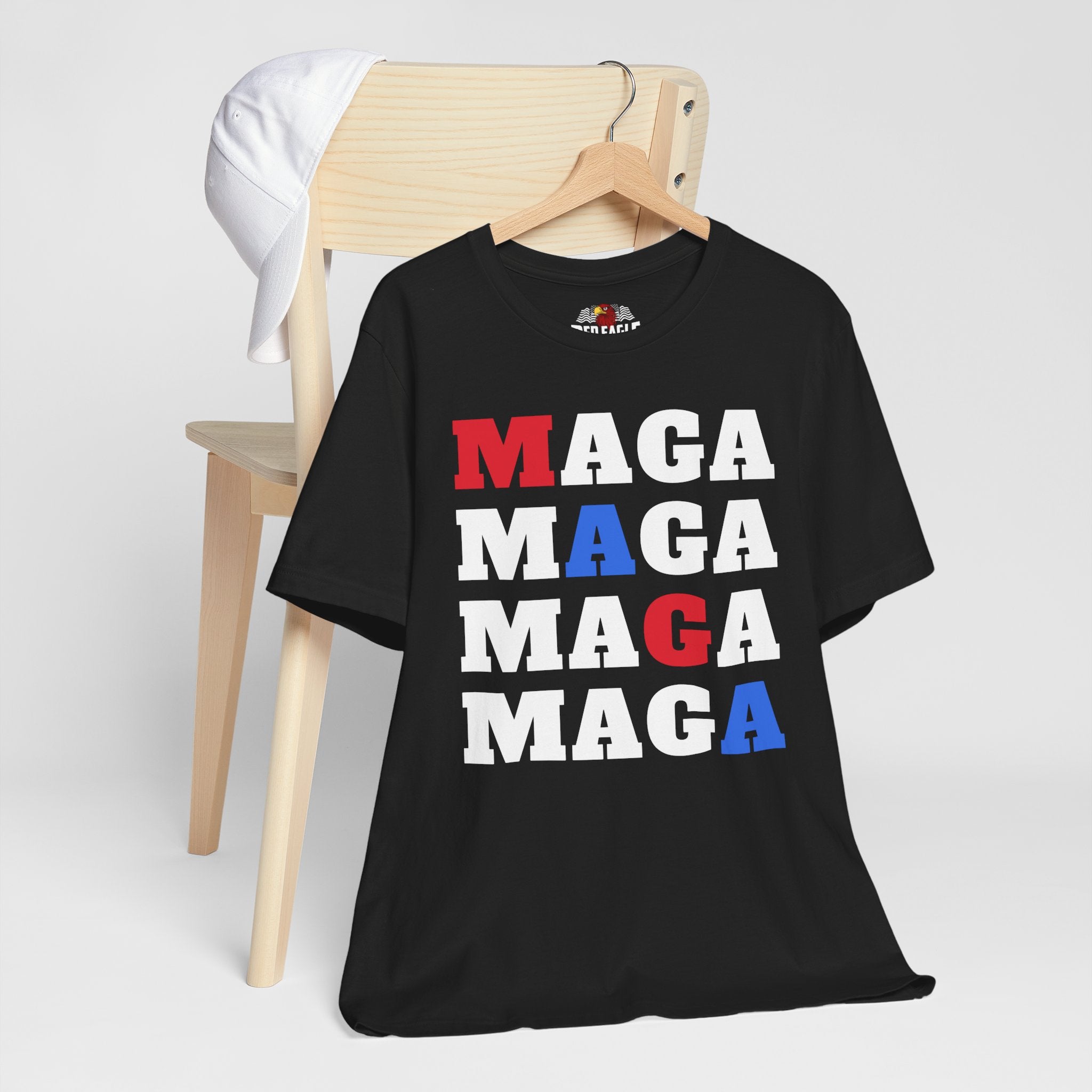 Black t-shirt with 'MAGA' text in red, white, and blue on a wooden chair.