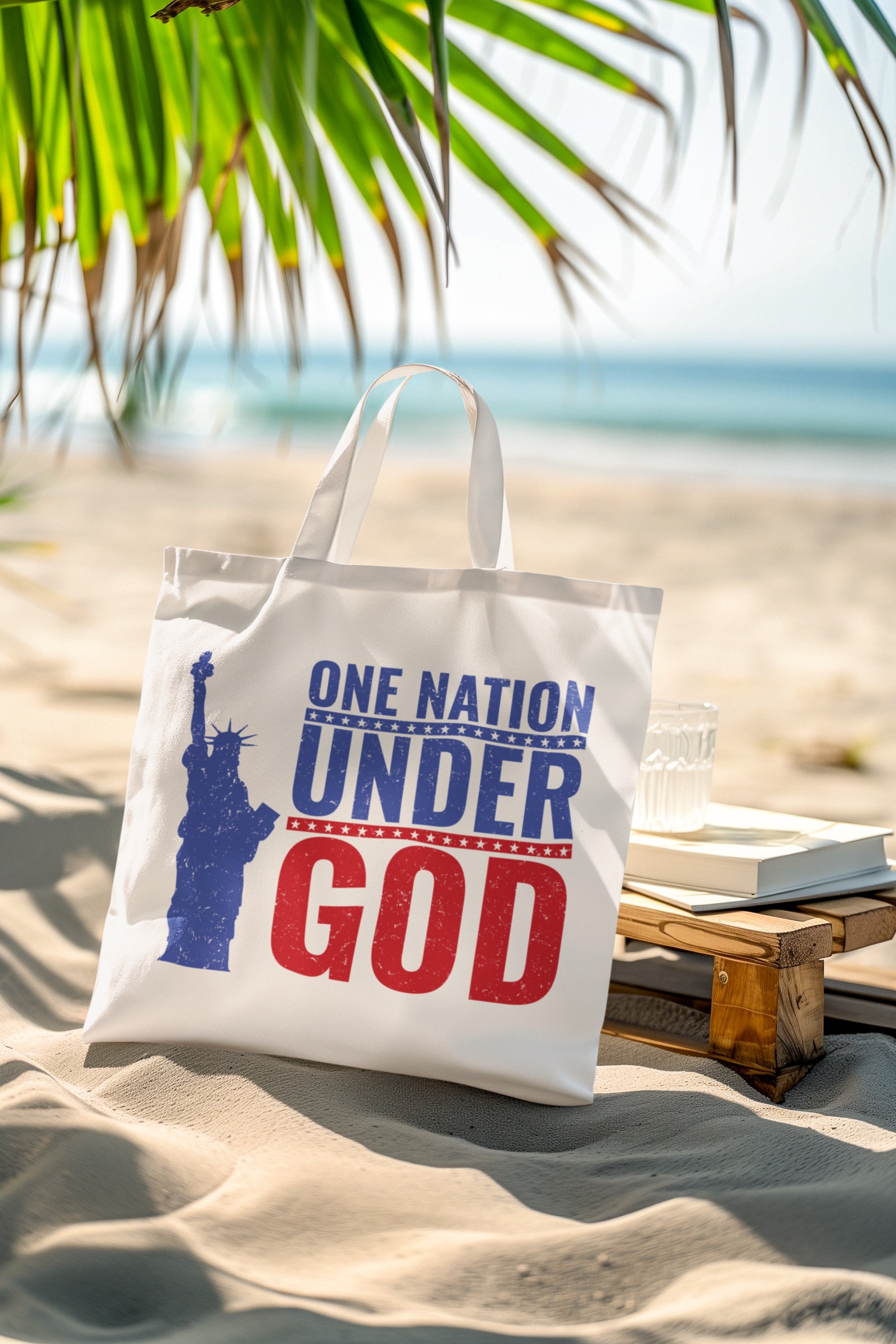 Tote bag with 'One Nation Under God' design on a beach