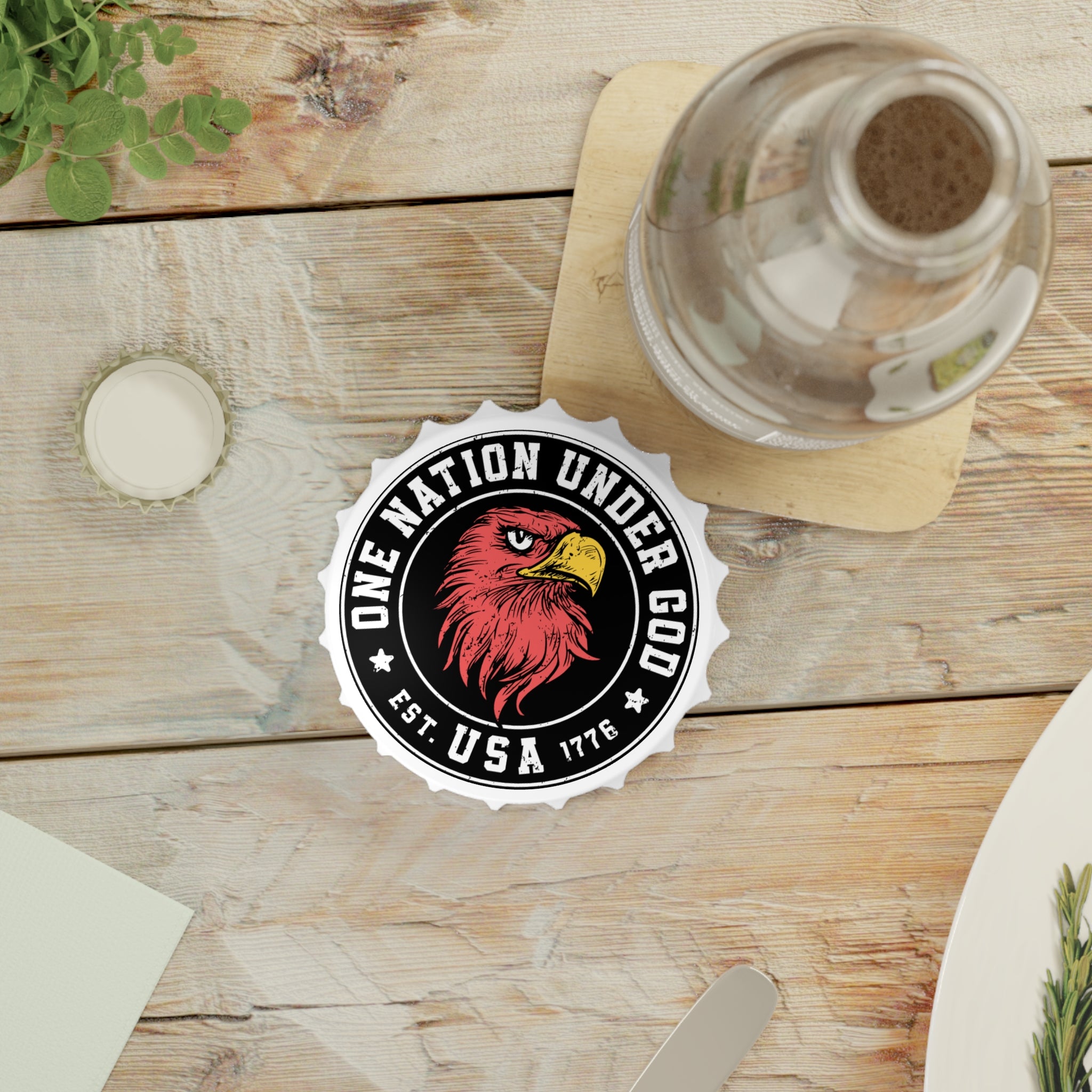 Table setting with a bottle opener fridge magnet with 'One Nation Under God' logo on a wooden table.