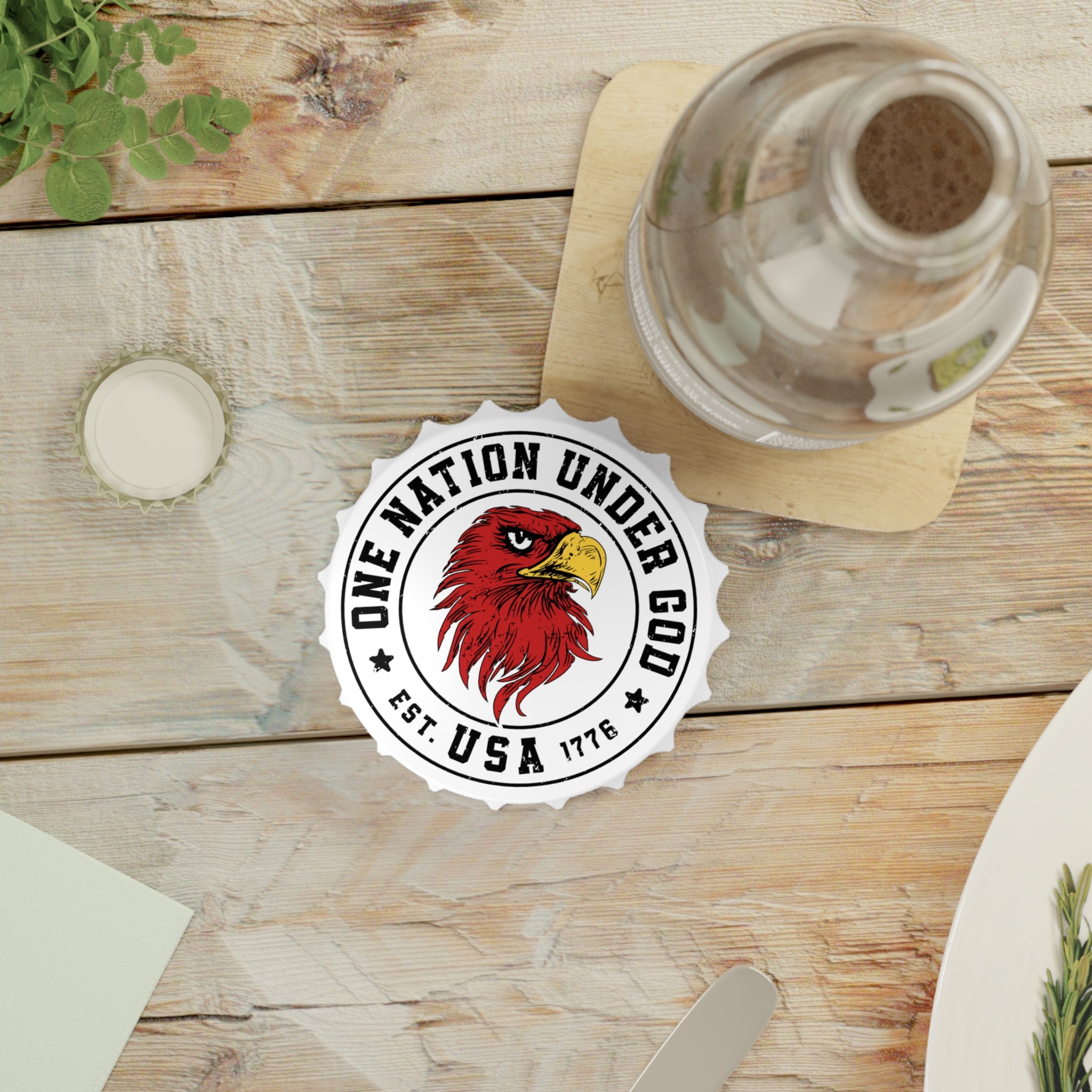 Bottle opener fridge magnet with 'One Nation Under God' logo on a wooden table with a bottle of water.