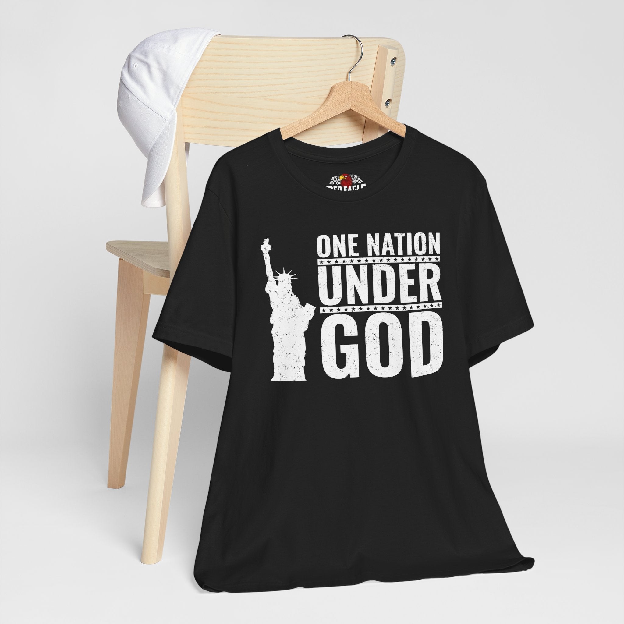 Black t-shirt with 'One Nation Under God' graphic on a wooden chair against a white background