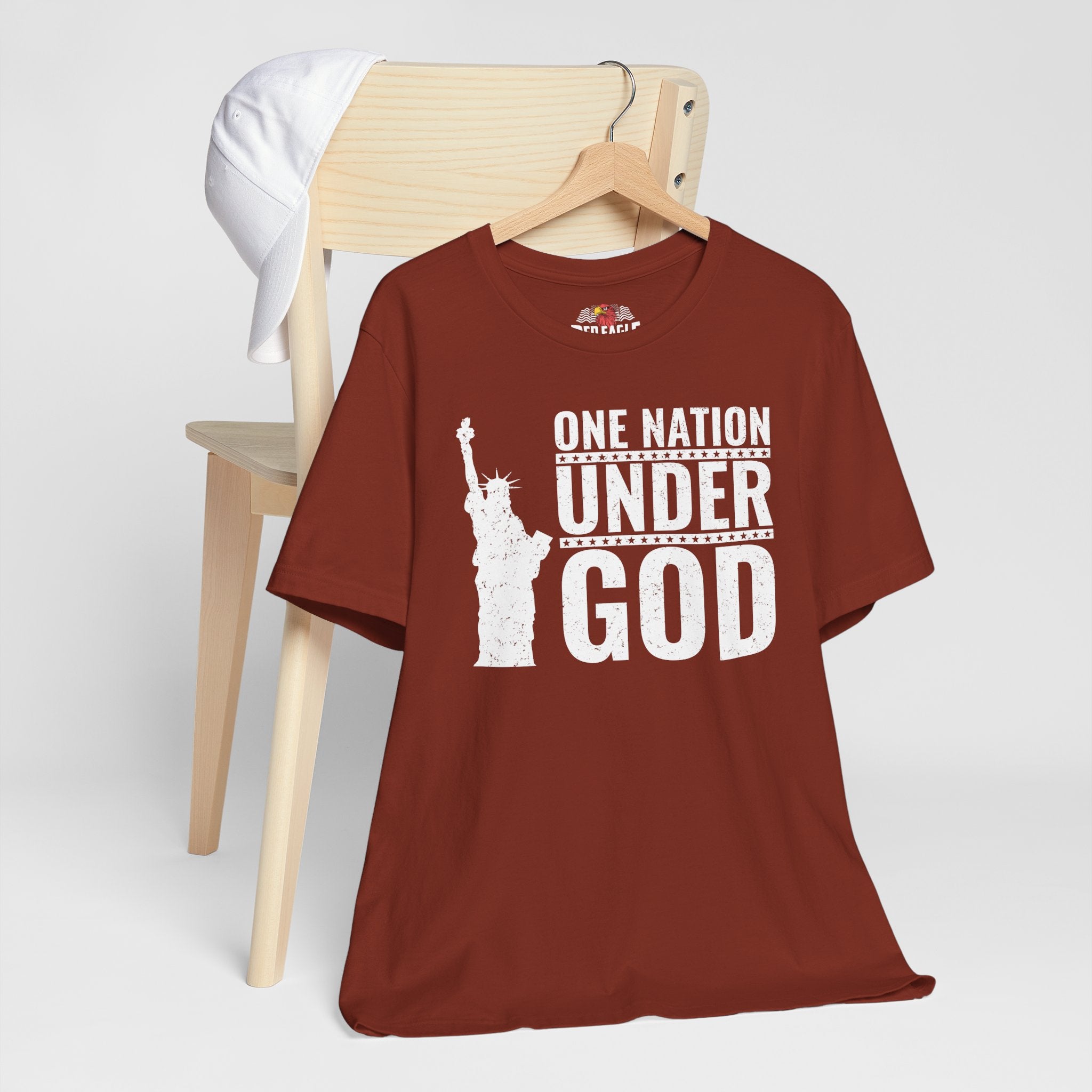 Rust t-shirt with 'One Nation Under God' graphic in white print on a wooden chair