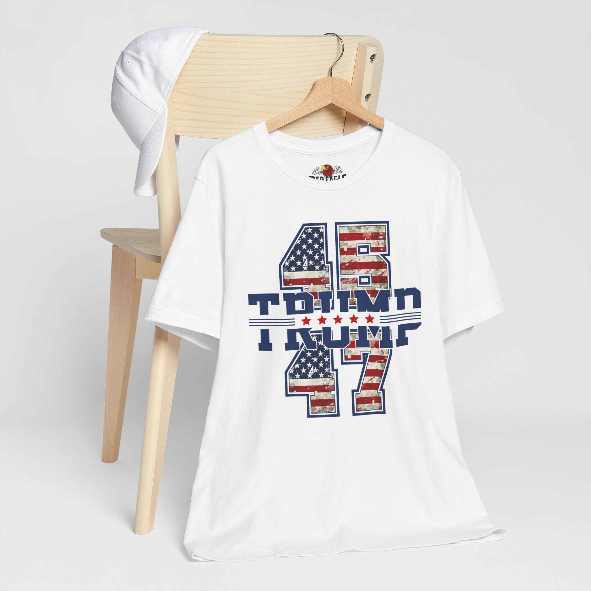 White t-shirt with graphic design on a wooden chair against a white background
