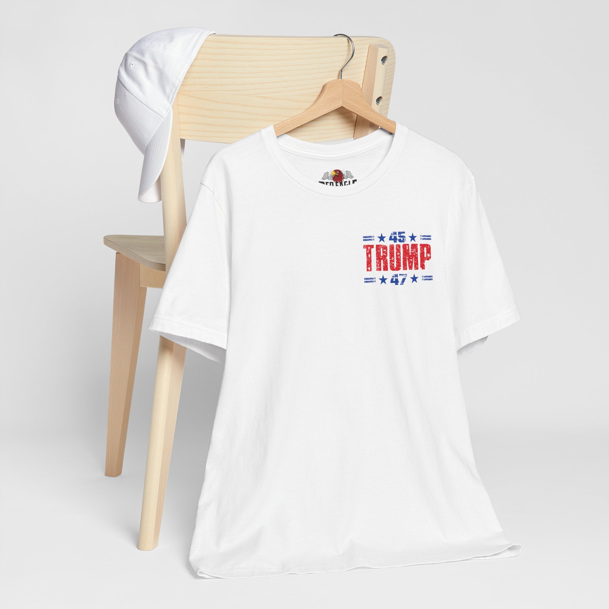 White t-shirt with 'TRUMP 47' design on a wooden chair against a white background