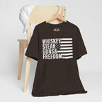 Brown t-shirt with 'Whiskey Steak Guns & Freedom' text and flag design on a wooden chair.
