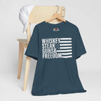 Deep teal t-shirt with 'Whiskey Steak Guns & Freedom' text on a wooden chair against a white background