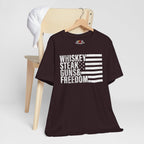 Oxblood Black t-shirt with 'Whiskey Steak Guns & Freedom' text and flag design on a wooden chair.