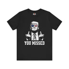Black t-shirt with graphic of a person making an gesture and text 'YOU MISSED' on a white background