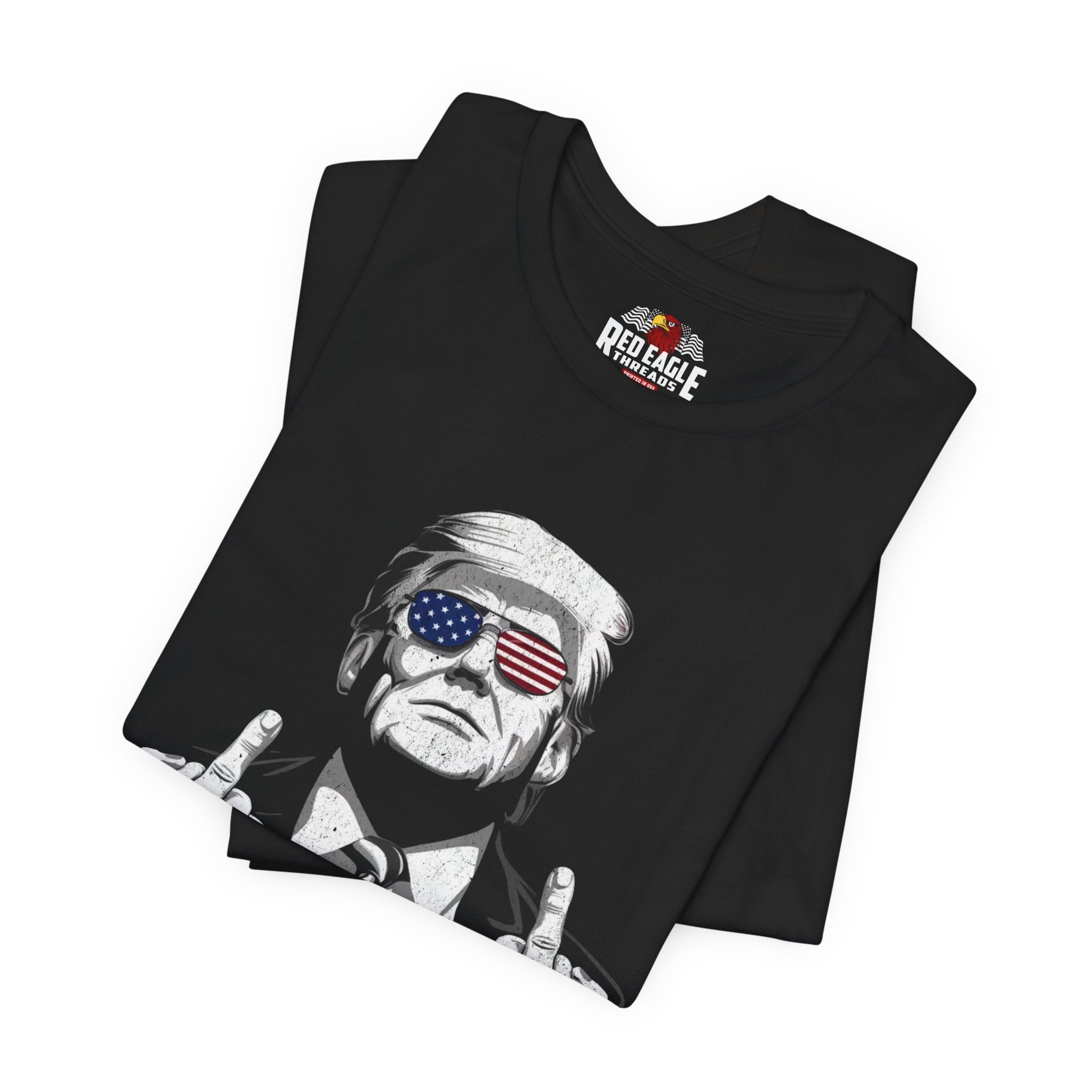 Black t-shirt with graphic design of a person wearing sunglasses with American flag design, folded on a white background.