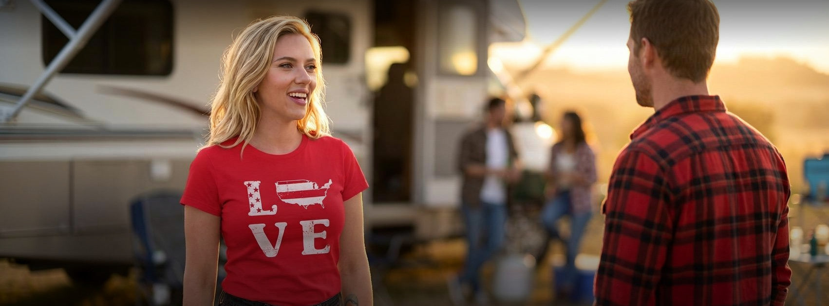 A woman in a red graphic t-shirt with 'LOVE' printed on it stands outdoors in front of an RV, smiling at a man in a red and black plaid flannel shirt.